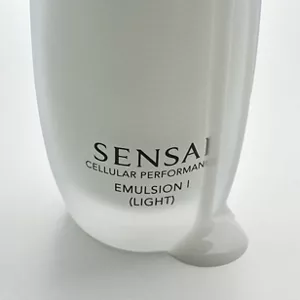 Gros plan sur le flacon de Cellular Performance Émulsion 1 (Légère) avec le produit qui s'écoule sur une surface grise pour mettre en valeur sa texture